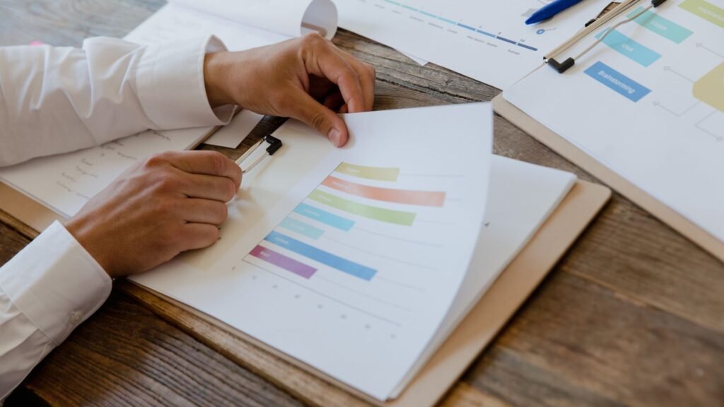 Hands reviewing a printed report with charts on a desk