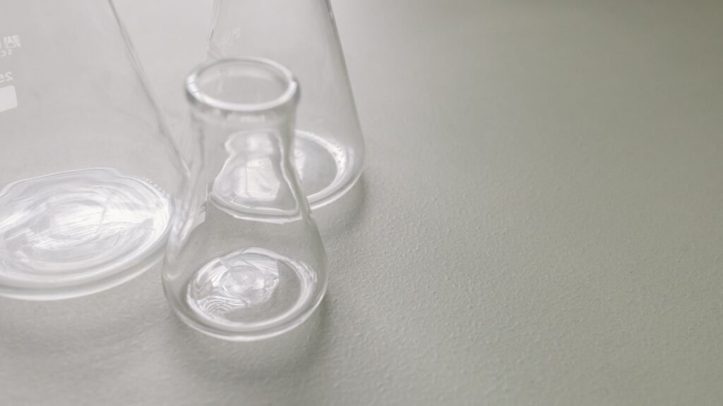 Close-up of clear Erlenmeyer flasks on a light surface