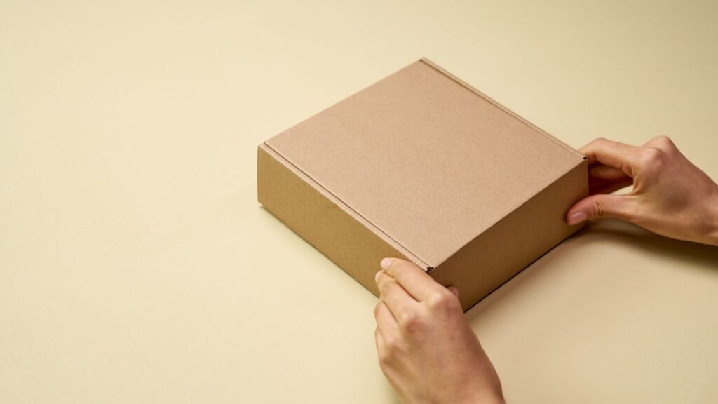 Hands opening a plain cardboard shipping box